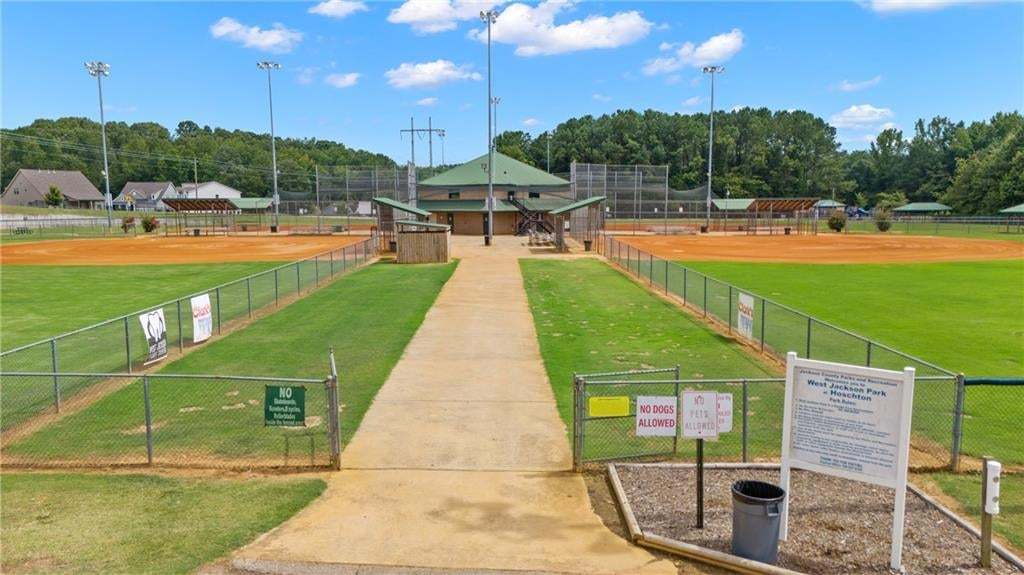 Concrete walkway leading to multiple fenced baseball fields with stadium lighting