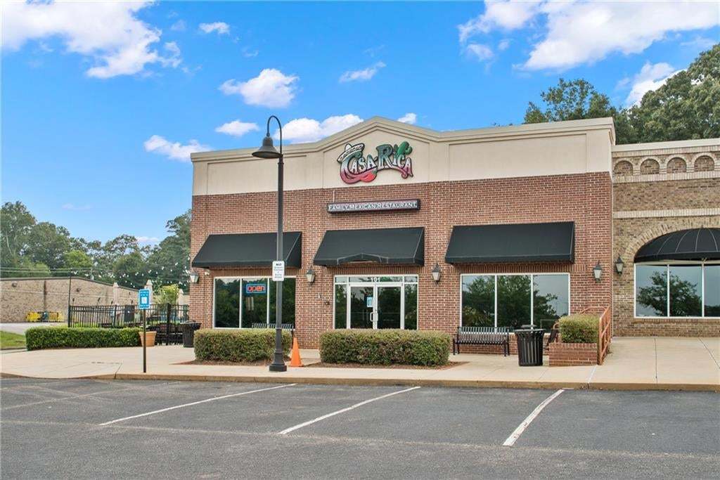 Brick facade commercial building featuring multiple storefronts, black awnings, and an arched window detail