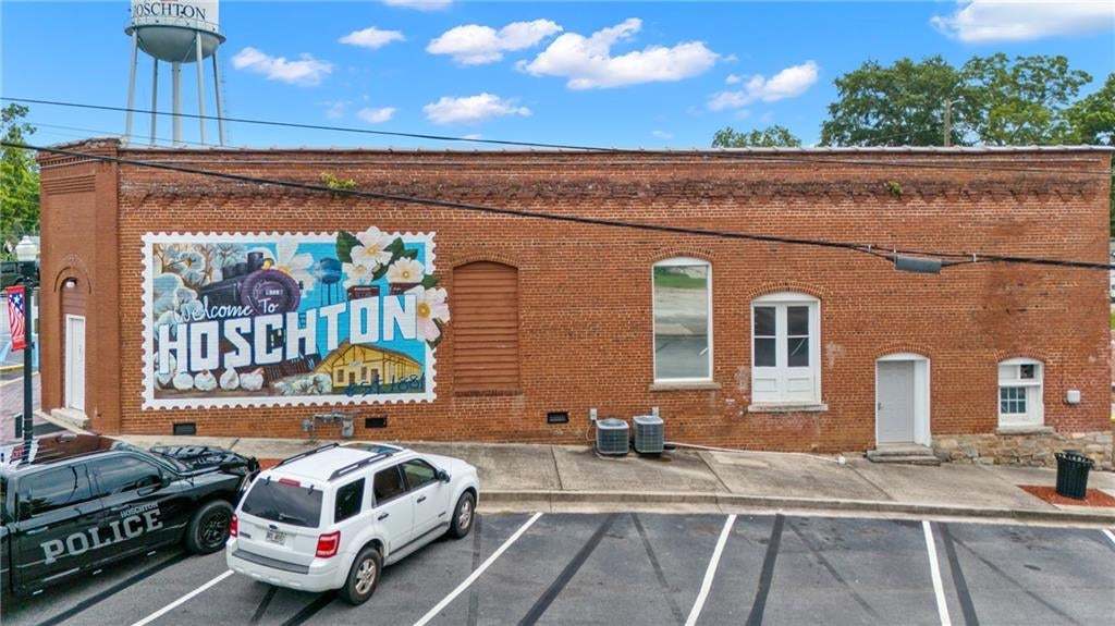 Brick facade commercial building featuring an artistic mural, multiple window openings, and an arched doorway