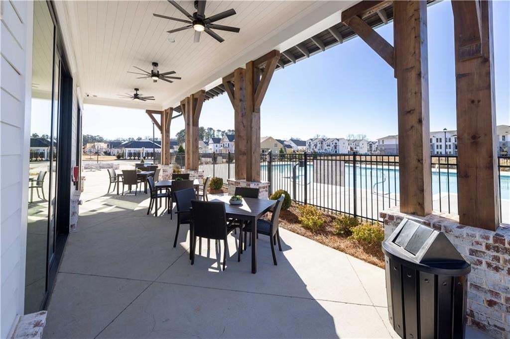 Covered outdoor patio with exposed beam ceiling, multiple ceiling fans, and concrete flooring