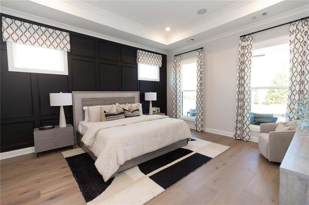 Hardwood-style flooring throughout, tray ceiling, accent wall with panel molding, recessed lighting, and large windows with integrated window seating