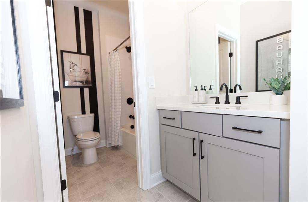 Bathroom featuring a gray vanity with black hardware, white countertop, and integrated sink