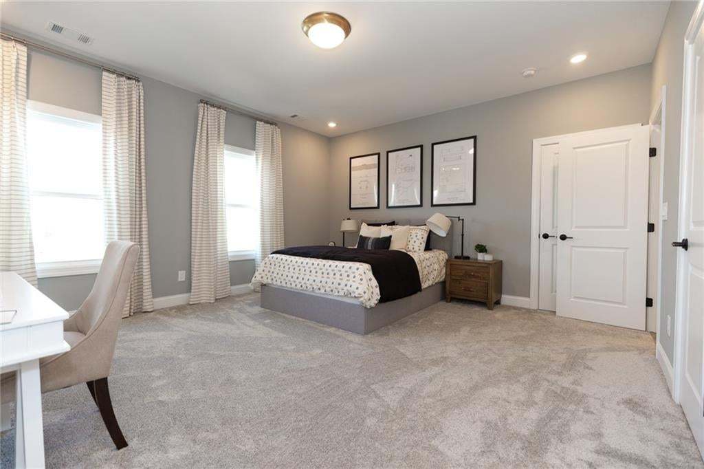 Spacious room featuring light gray carpeting, neutral-toned walls, two panel doors with matte black hardware, and recessed lighting