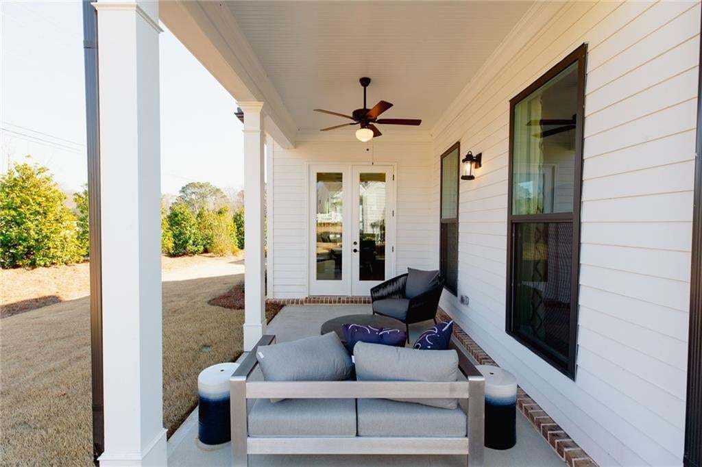 Covered patio featuring a ceiling fan, dual exterior light fixtures, and a white plank-sided exterior
