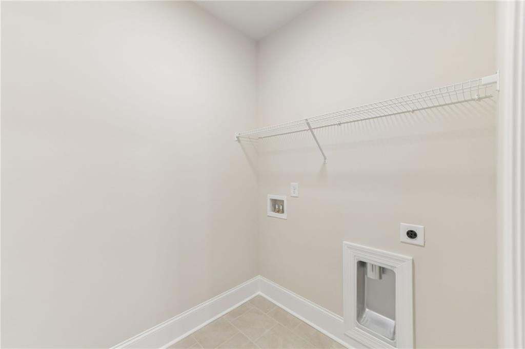 Utility area featuring light neutral wall tones, white trim, and a wire shelf