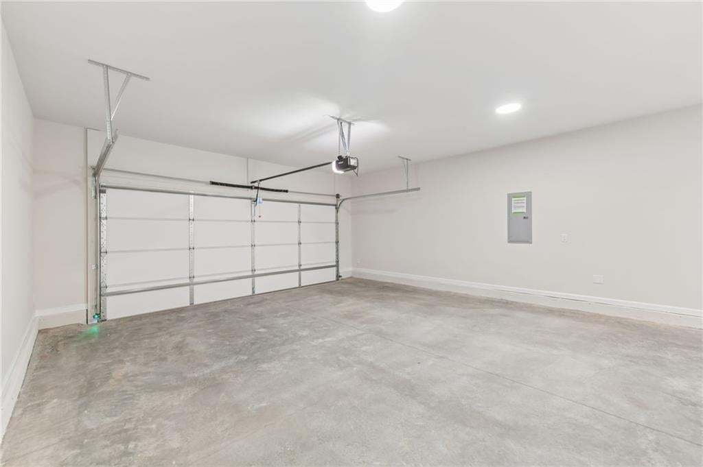 Spacious garage with concrete flooring, white walls, and an automatic overhead door