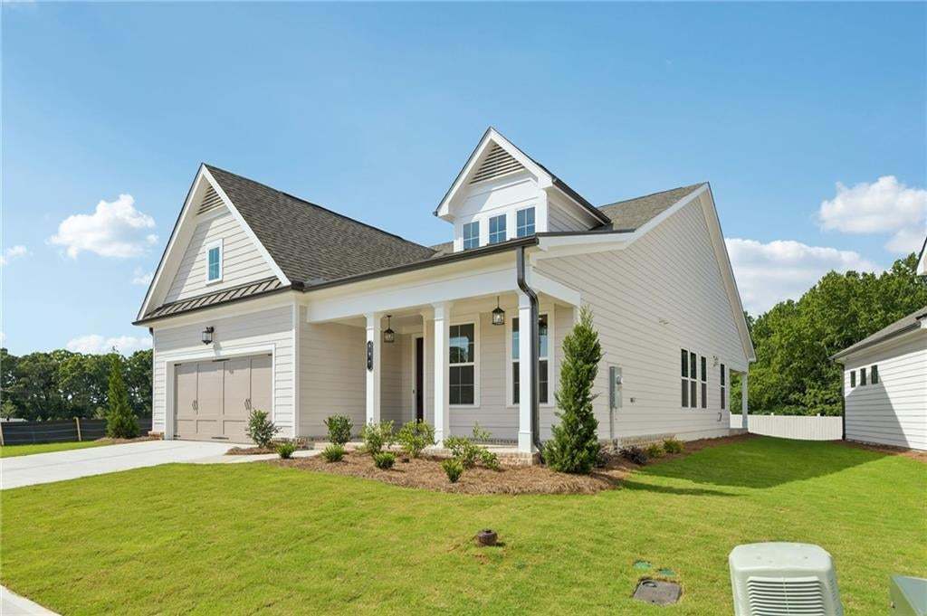 White horizontal siding exterior with a dark shingle roof, attached two-car garage, covered porch, and white column accents