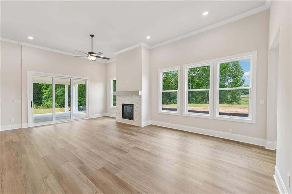 Spacious room featuring wood-finish flooring, a contemporary fireplace, and a ceiling fan