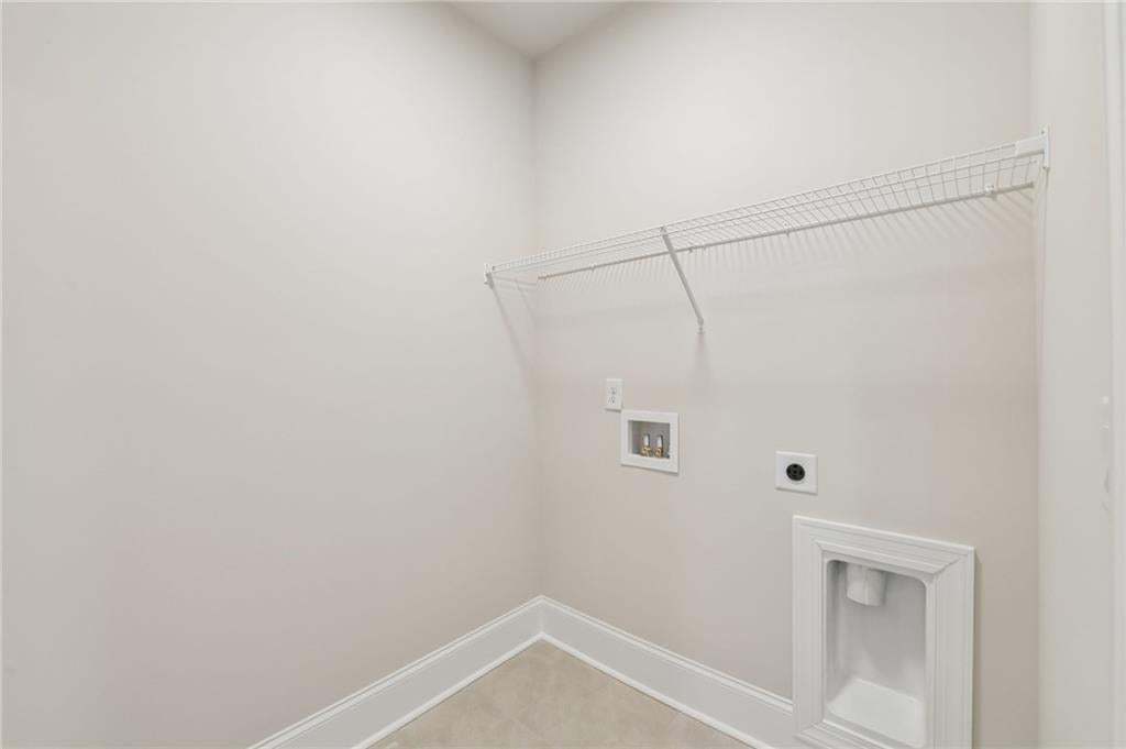 Laundry area featuring a wire storage shelf, utility hookups, and light-toned flooring