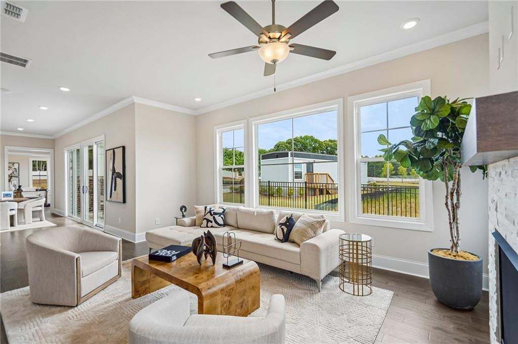 Living area featuring wood-finish flooring, recessed lighting, a ceiling fan, and expansive windows with muntins