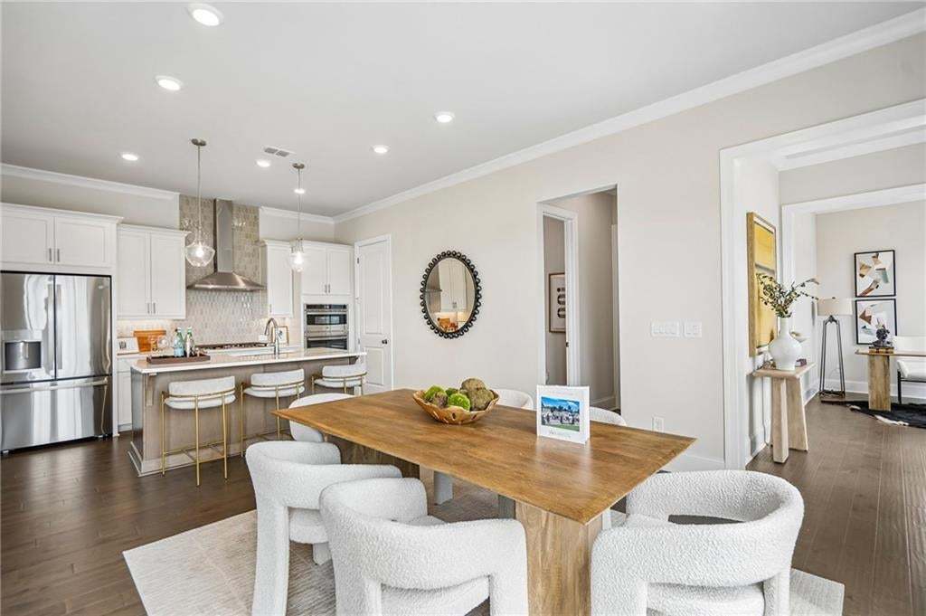 Kitchen featuring white shaker-style cabinetry, stainless steel appliances, stone-surface island, decorative tile backsplash, and wood-finish flooring