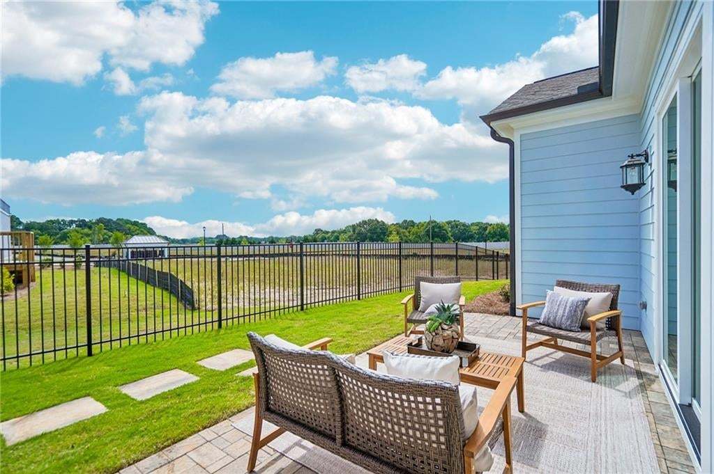 Paver patio with horizontal lap siding exterior, black metal fencing, and wall-mounted exterior lighting