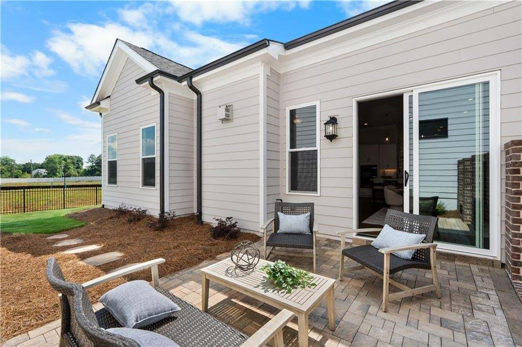 Exterior patio featuring concrete paver flooring, horizontal lap siding, a sliding glass door, and a black metal perimeter fence