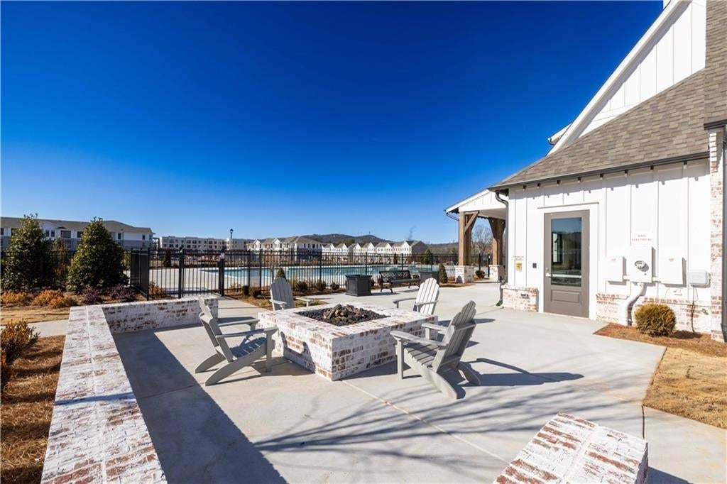Concrete patio featuring a built-in brick fire pit, low-profile perimeter brick seating walls, and board-and-batten exterior siding