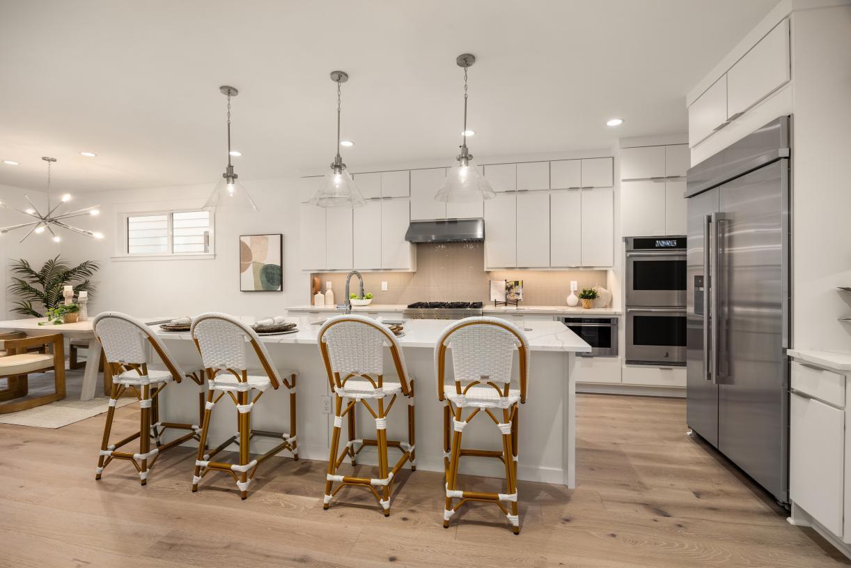 Kitchen features double-stacked contemporary white flat panel cabinetry