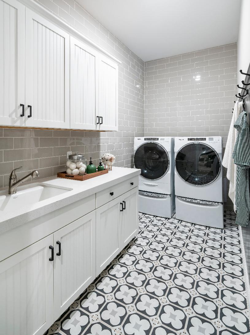 Laundry room with white cabinets, subway tile, quartz countertops and single basin sink