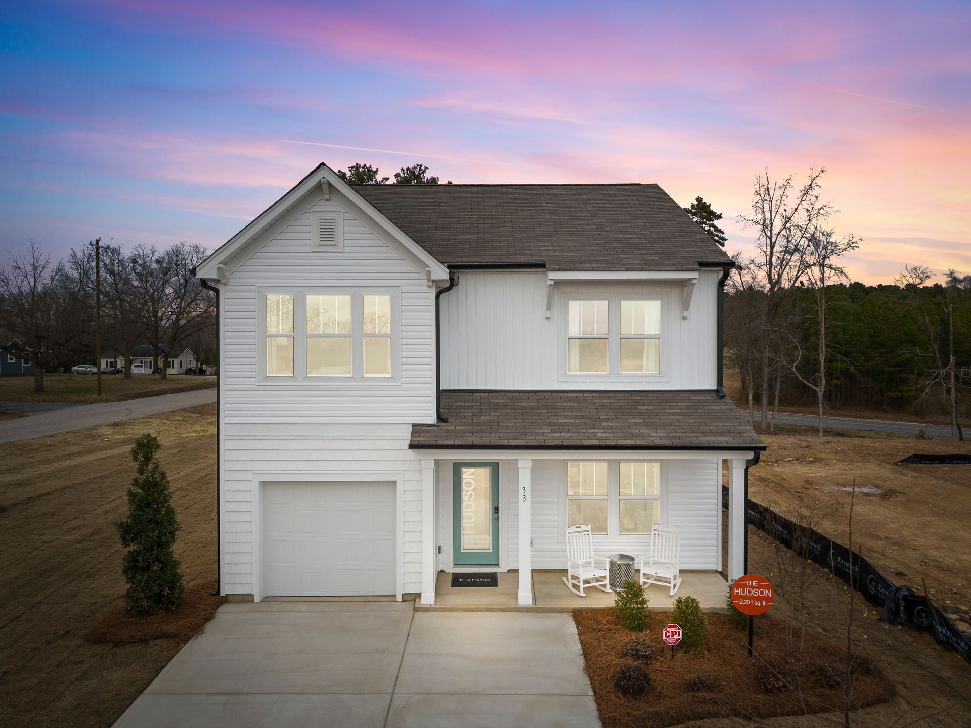 An aerial view of a white house with a porch and a garage.