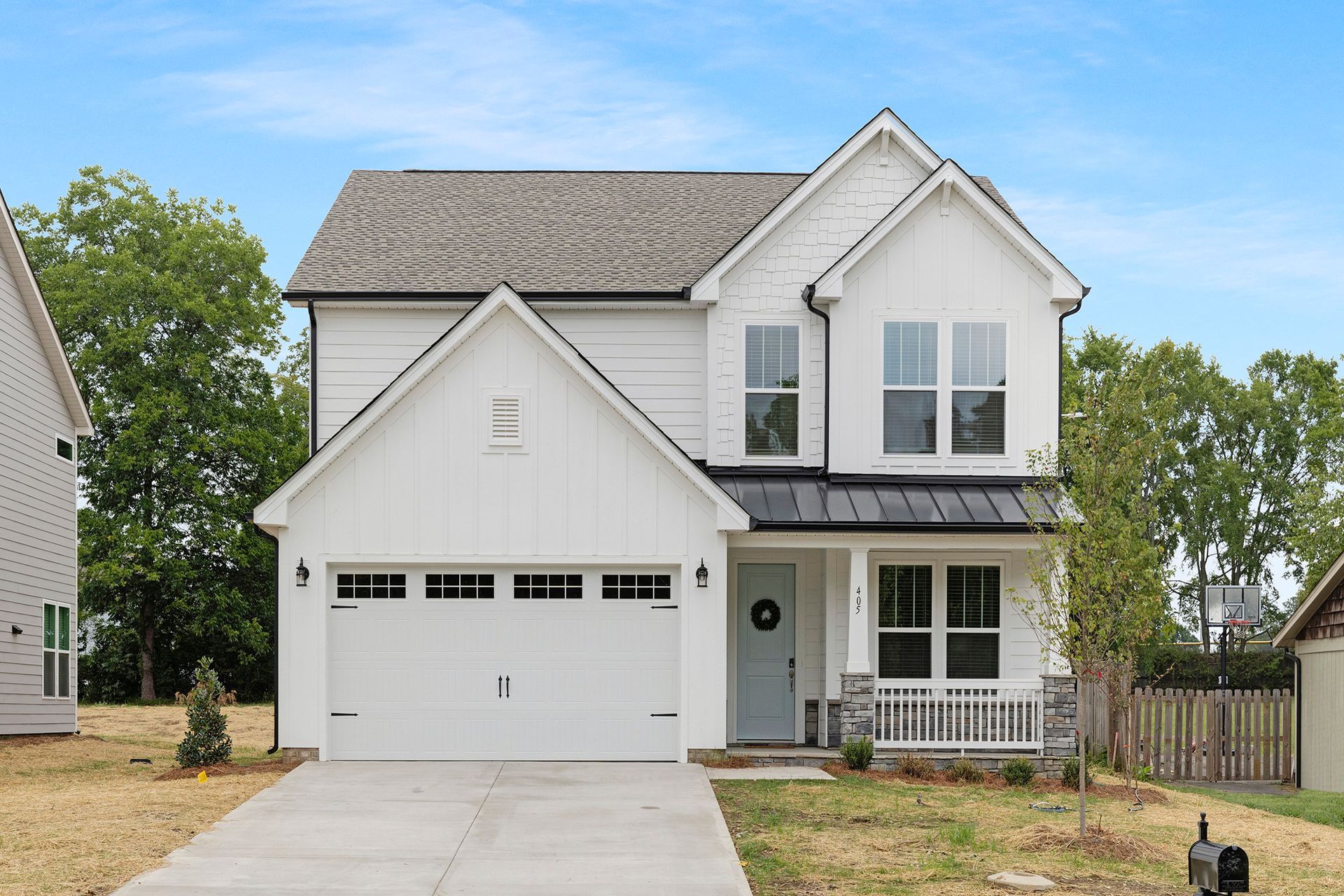 A white house with a black roof and a white garage door is for sale.