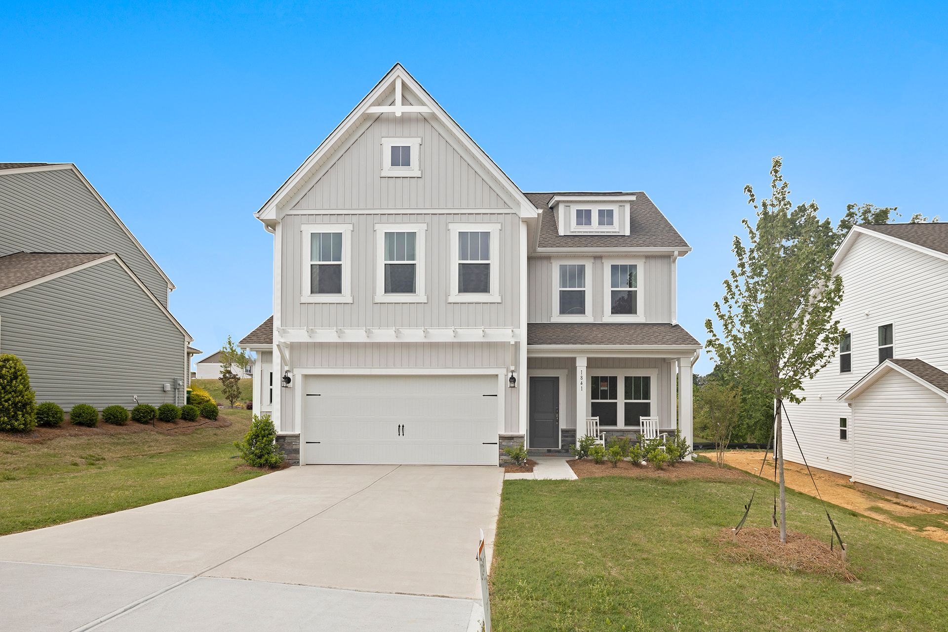 A large white house with a gray roof and a large driveway.