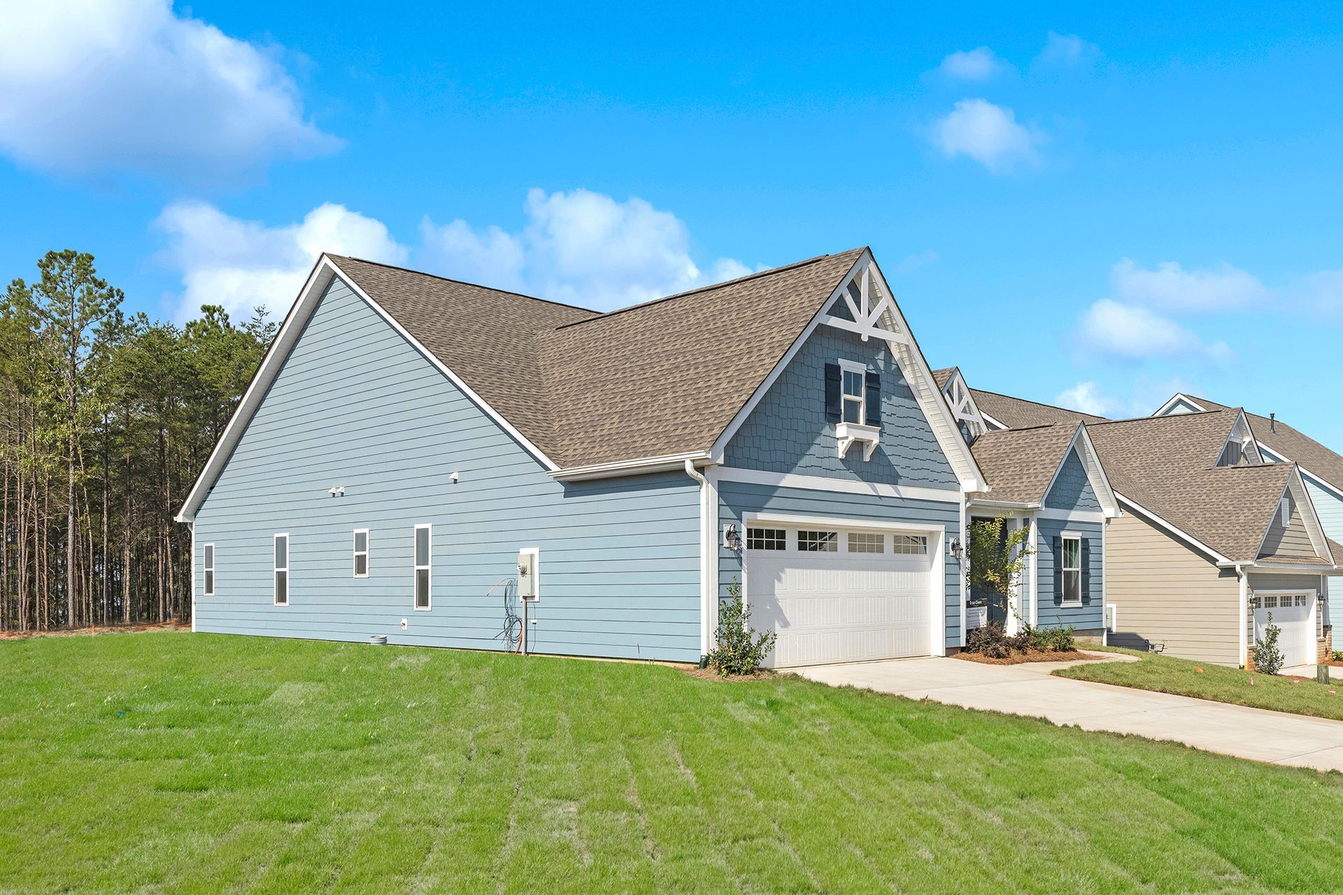 A blue house with a brown roof is sitting on top of a lush green hillside.
