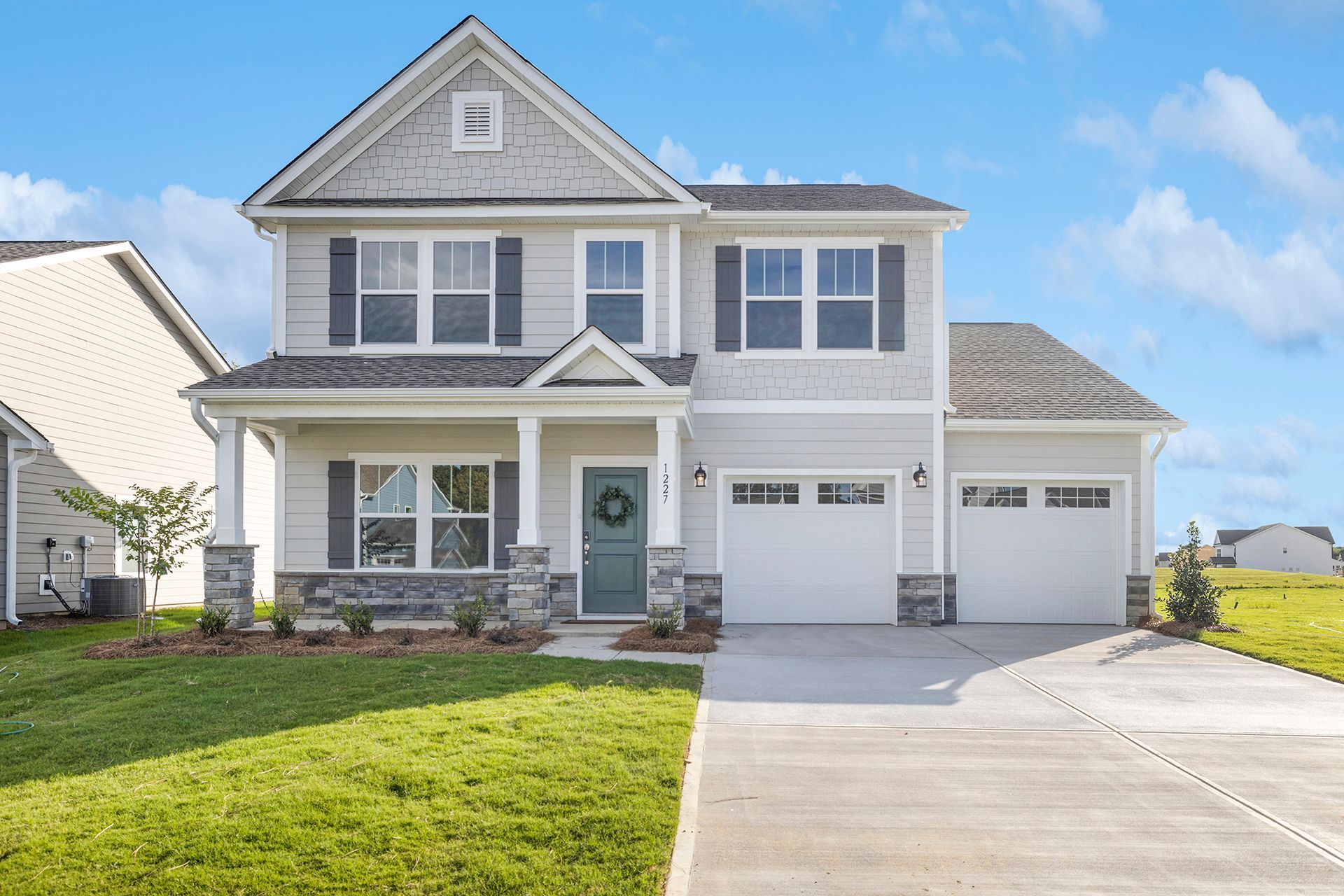 A large white house with a large driveway in front of it.