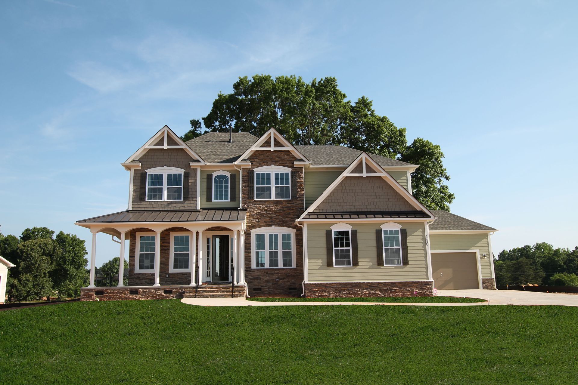 A large house is sitting on top of a lush green field.