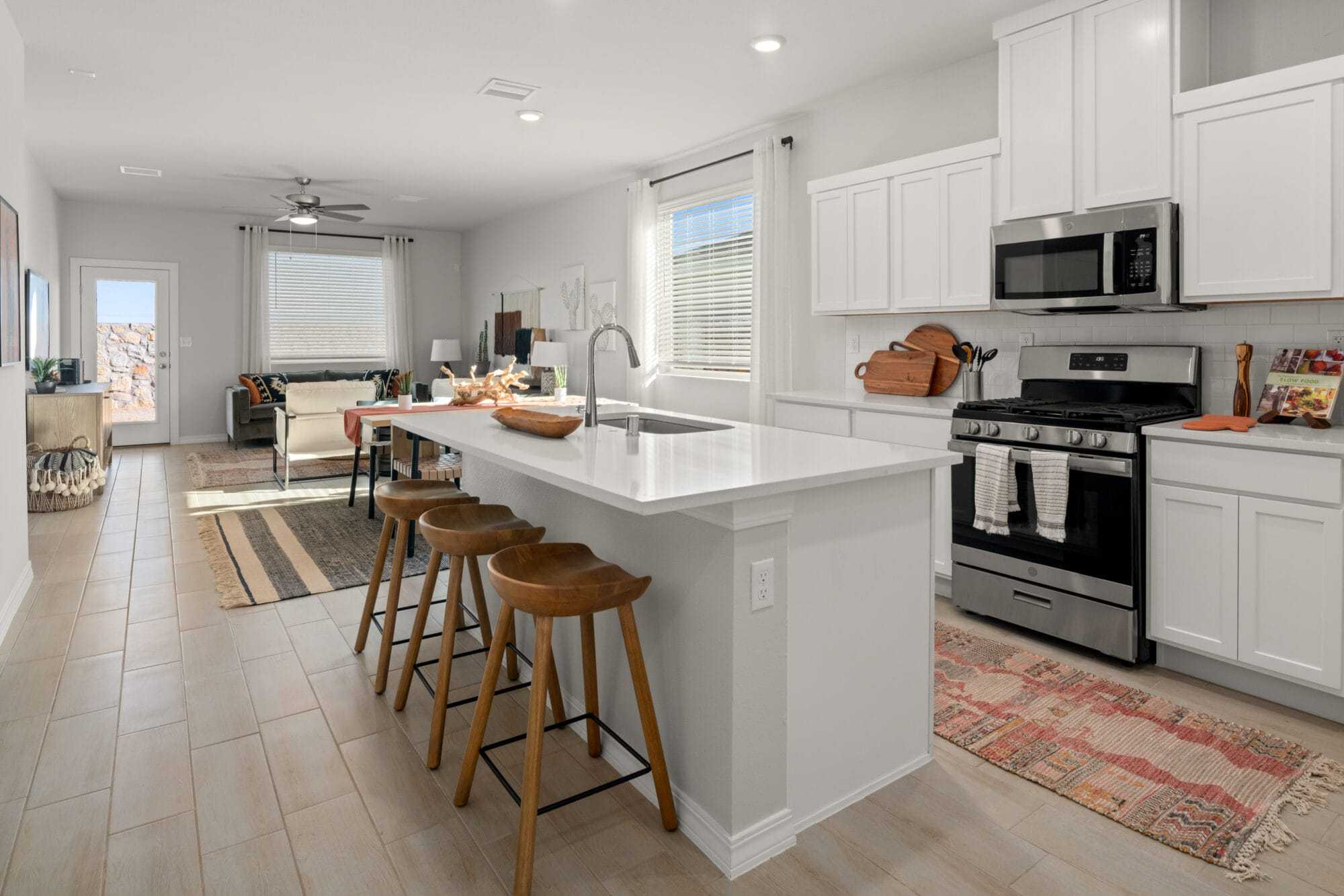 The Texas Olive floorplan showcases a bright island kitchen with white cabinetry and a seamless open layout connecting the dining and living spaces.