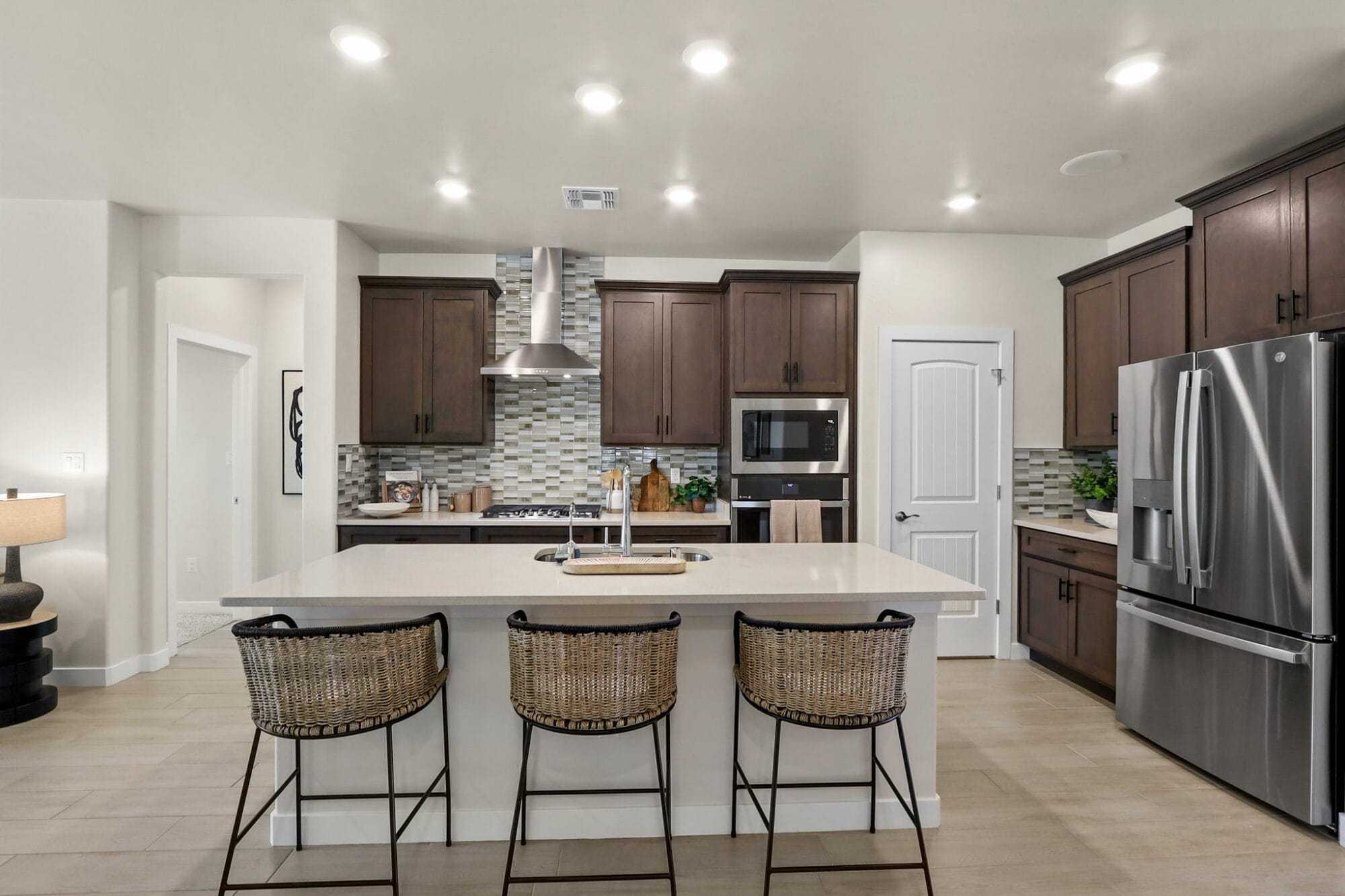 this open concept kitchen features a large island with seating for three dark wood cabinetry, and stainless steel appliances perfect for entertaining and everyday living.