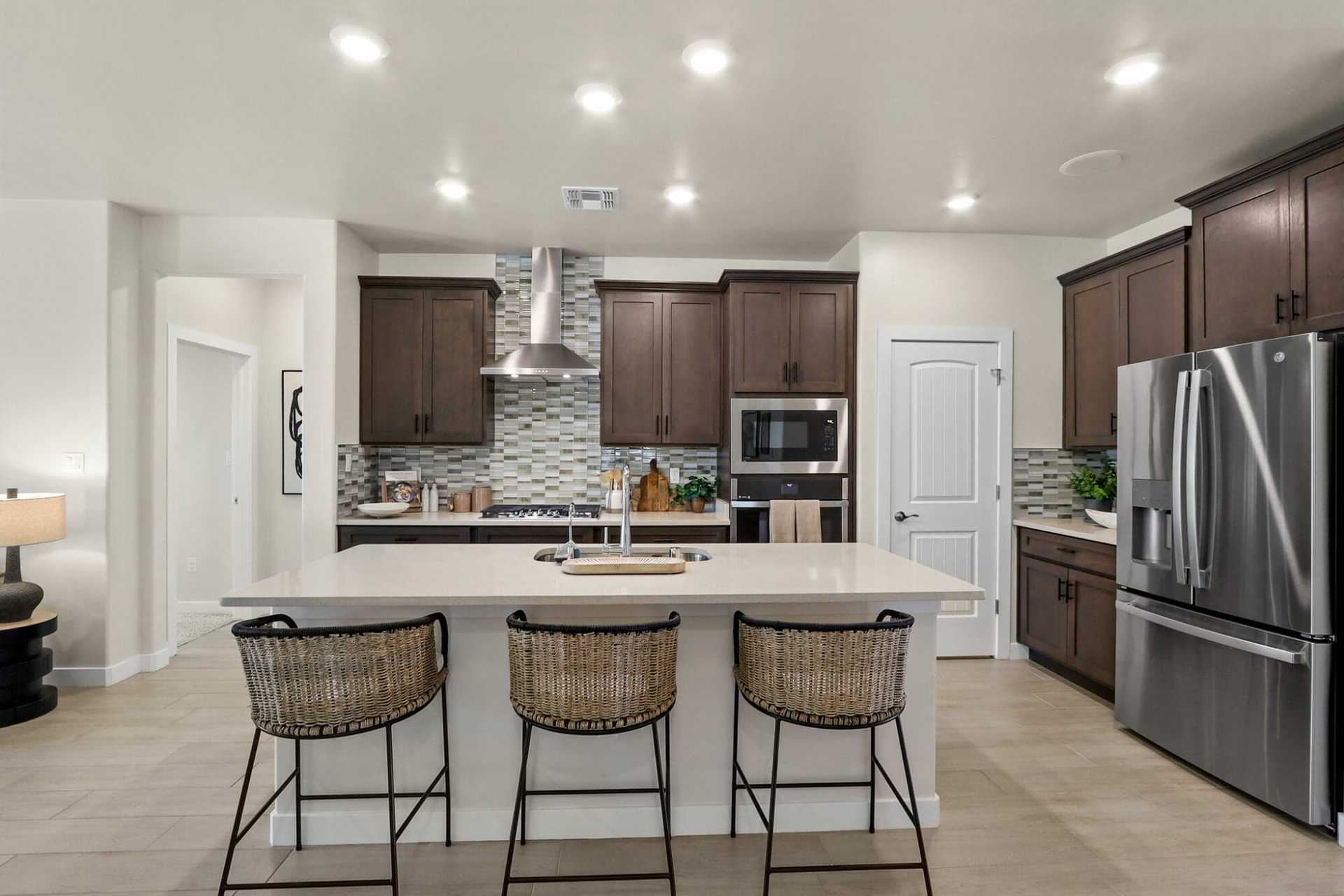 this open concept kitchen features a large island with seating for three dark wood cabinetry, and stainless steel appliances perfect for entertaining and everyday living.
