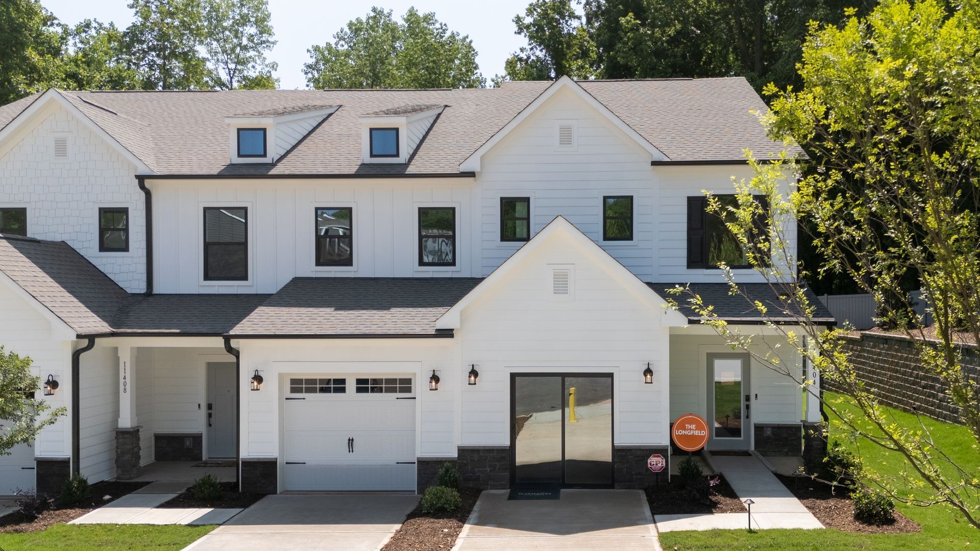 A large white house with a black roof and a garage.