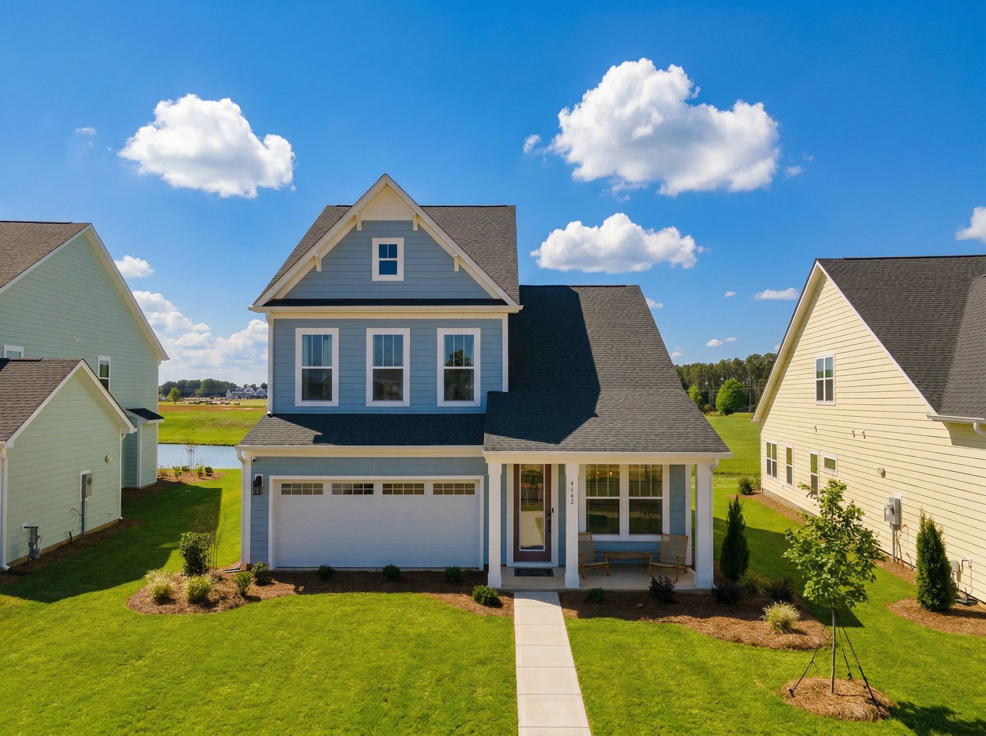 Blue two-story suburban house with white trim, front lawn, and garage under a sunny sky
