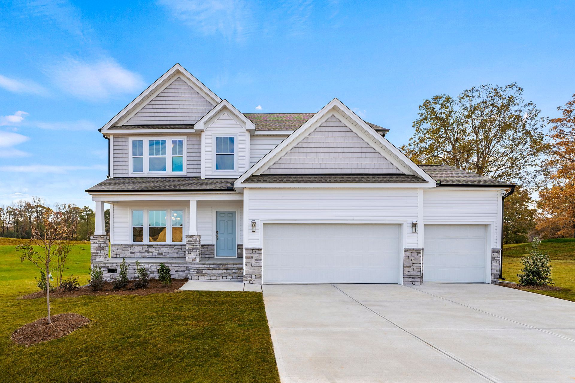 A large white house with a concrete driveway in front of it.