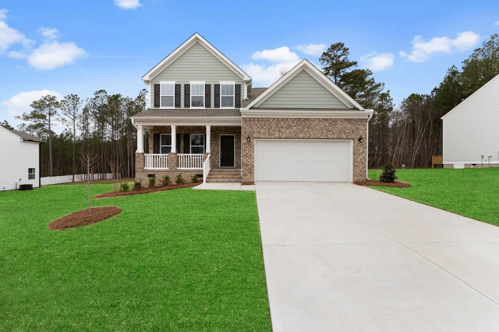 A large house with a white garage door is sitting on top of a lush green lawn.