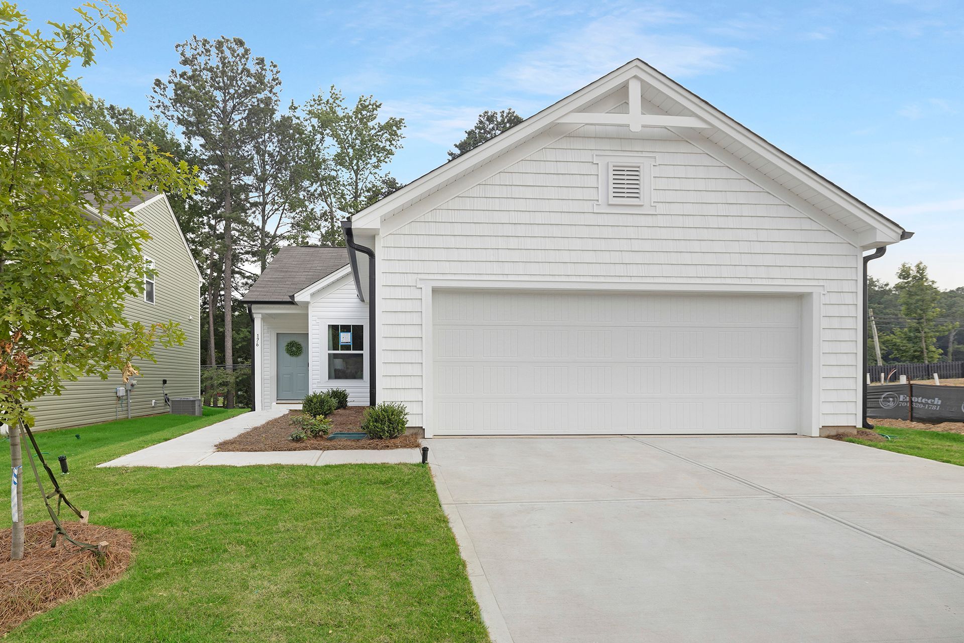 A white house with a large garage and a concrete driveway.
