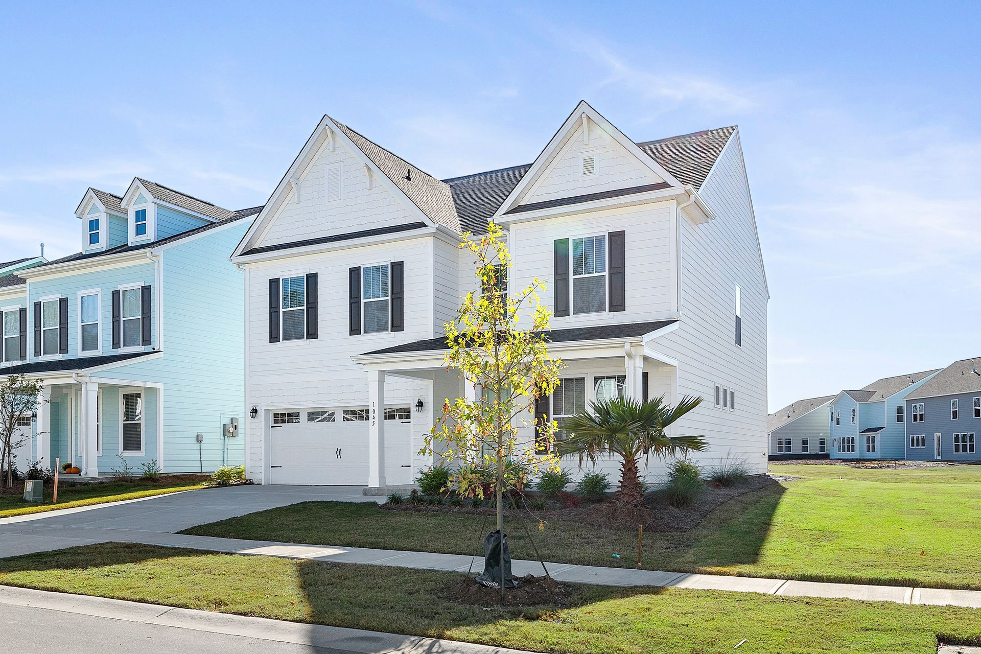 A white house with a blue house in the background in a residential area.