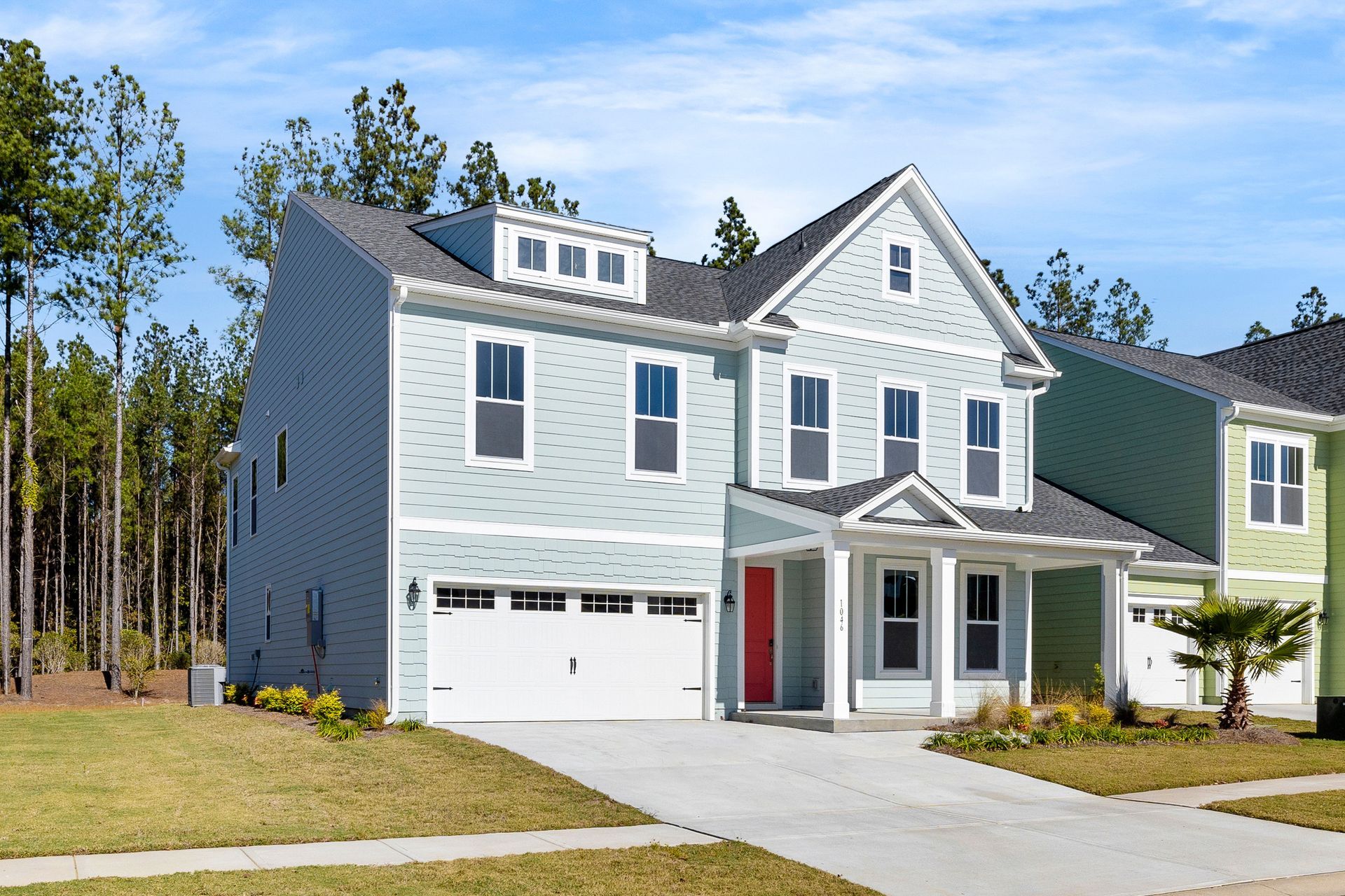 A white house with a red door is in a residential neighborhood.