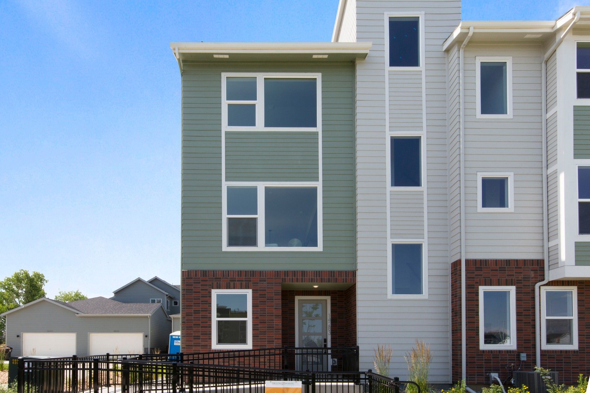 Contemporary Townhouse at Dillon Pointe with Brick Accents:Featuring stylish green siding, chic brickwork, and generous windows, this Dillon Pointe home epitomizes modern luxury.
