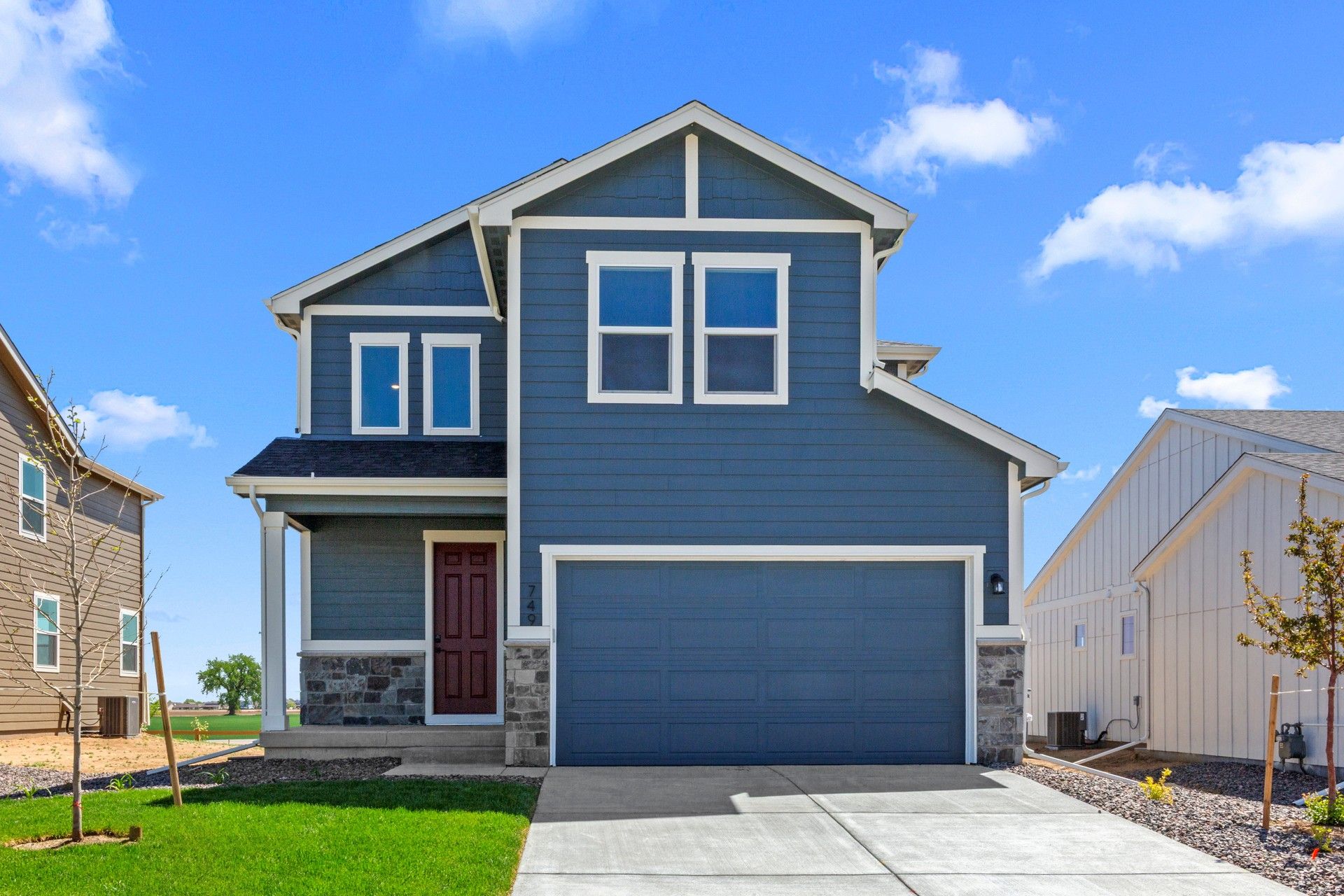 Contemporary Blue Home with Red Door in Colorado Suburb:Experience elegance in Colorado; blue siding, sleek gabled roof, stone accents enhance luxury appeal.