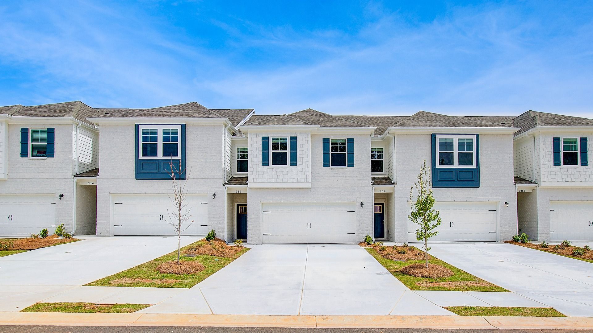 Austin:Two-story Austin Alternate townhome with light exterior, modern blue accents, and two-car garage at Bowers Farm Townhomes.