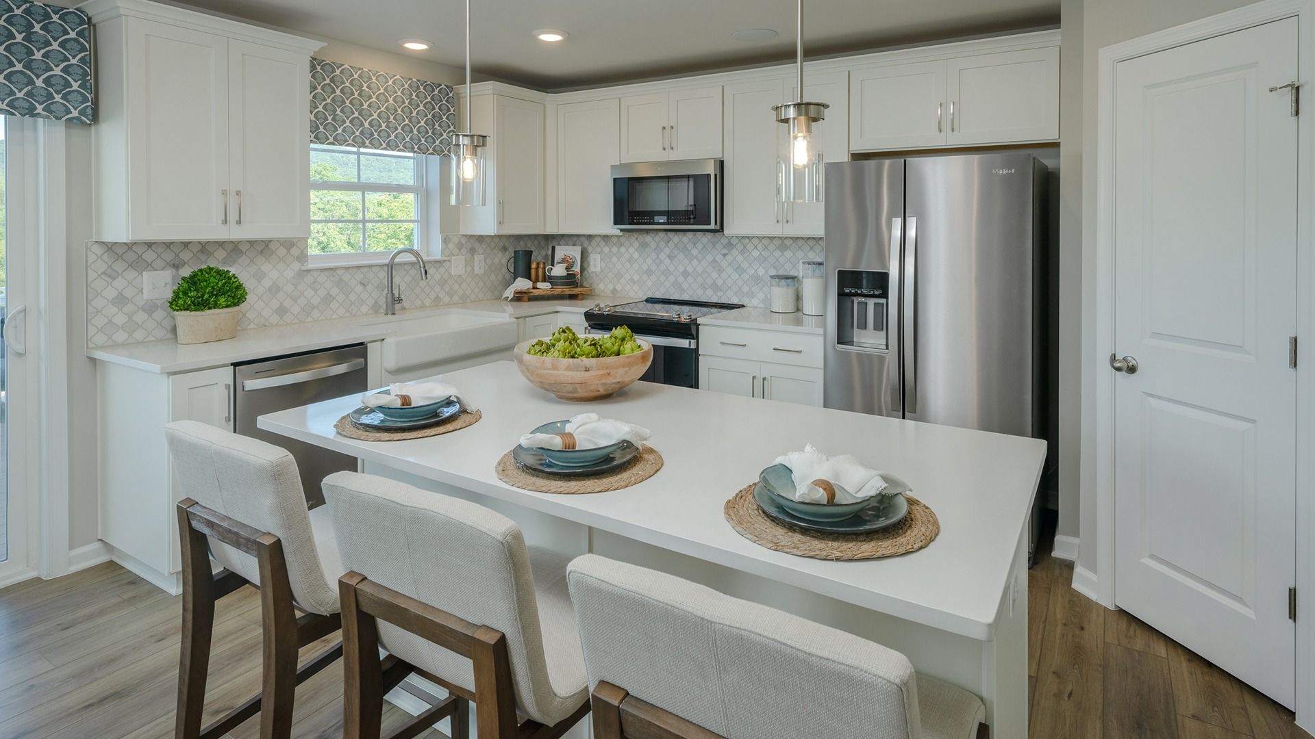 Carnegie Kitchen:Island kitchen with white upper cabinets & gray lower cabinets, white counters, stainless appliances, large window above sink