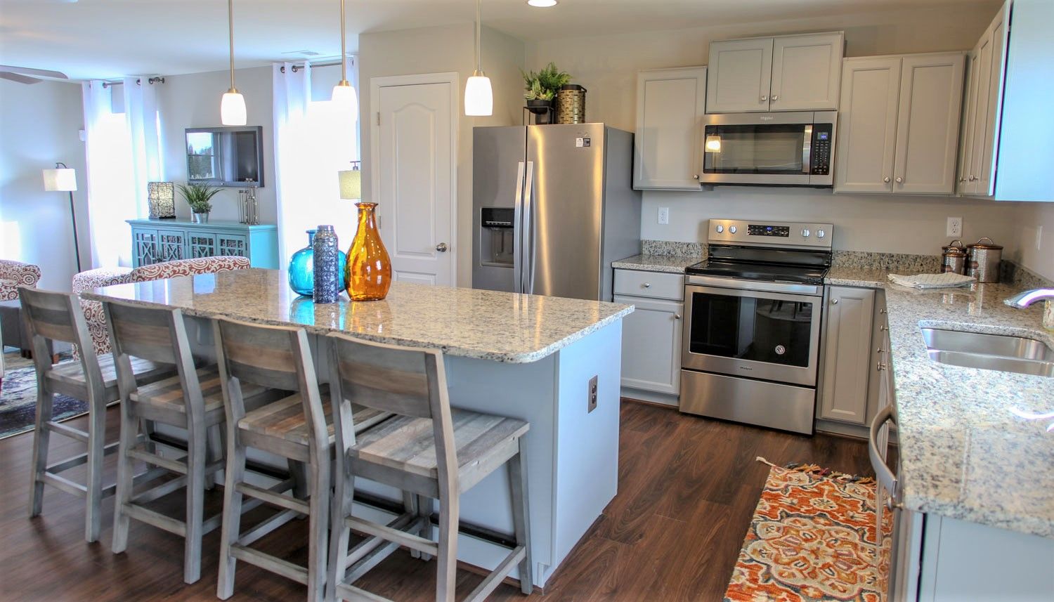 Kitchen with light cabinets, large island, gray counters, stainless appliances & open to family room