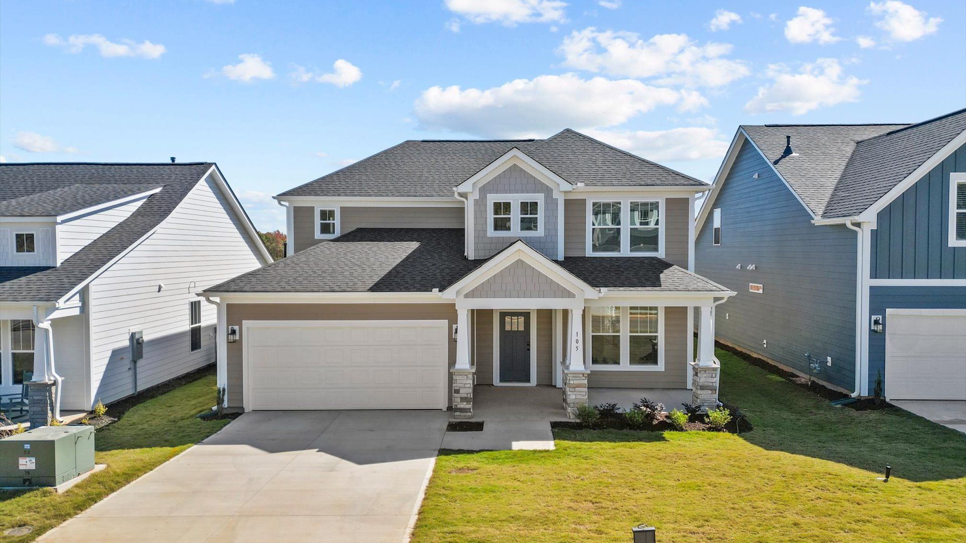 Exterior of two story home with neutral siding at Pelham Crossing in Greenville, SC:Two story home in Greenville, SC with neutral exterior, two car garage, and stone columns at Pelham Crossing by DRB Homes