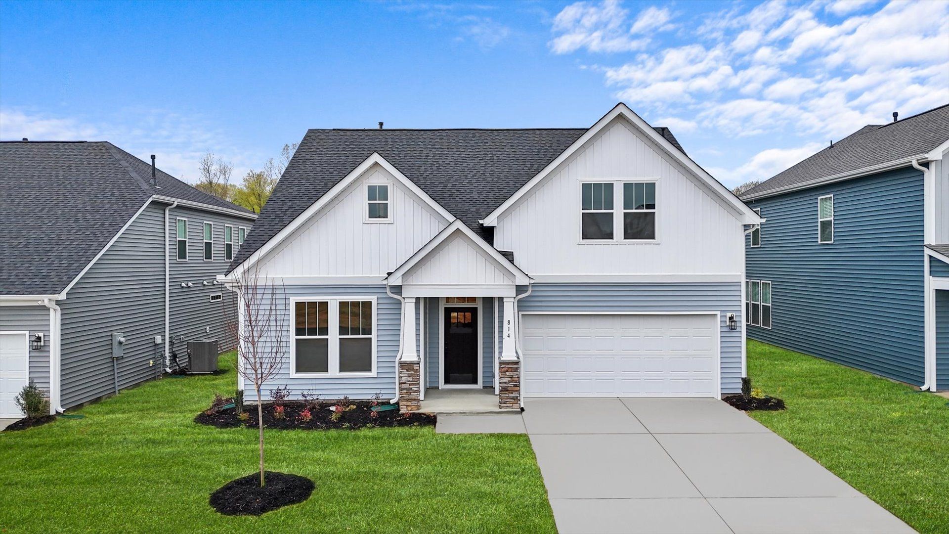 Exterior of two story home at Iris Meadows by DRB Homes in Moore, SC:Light blue exterior charming two story home with stone columns and two car garage at Iris Meadows by DRB Homes in Moore, SC