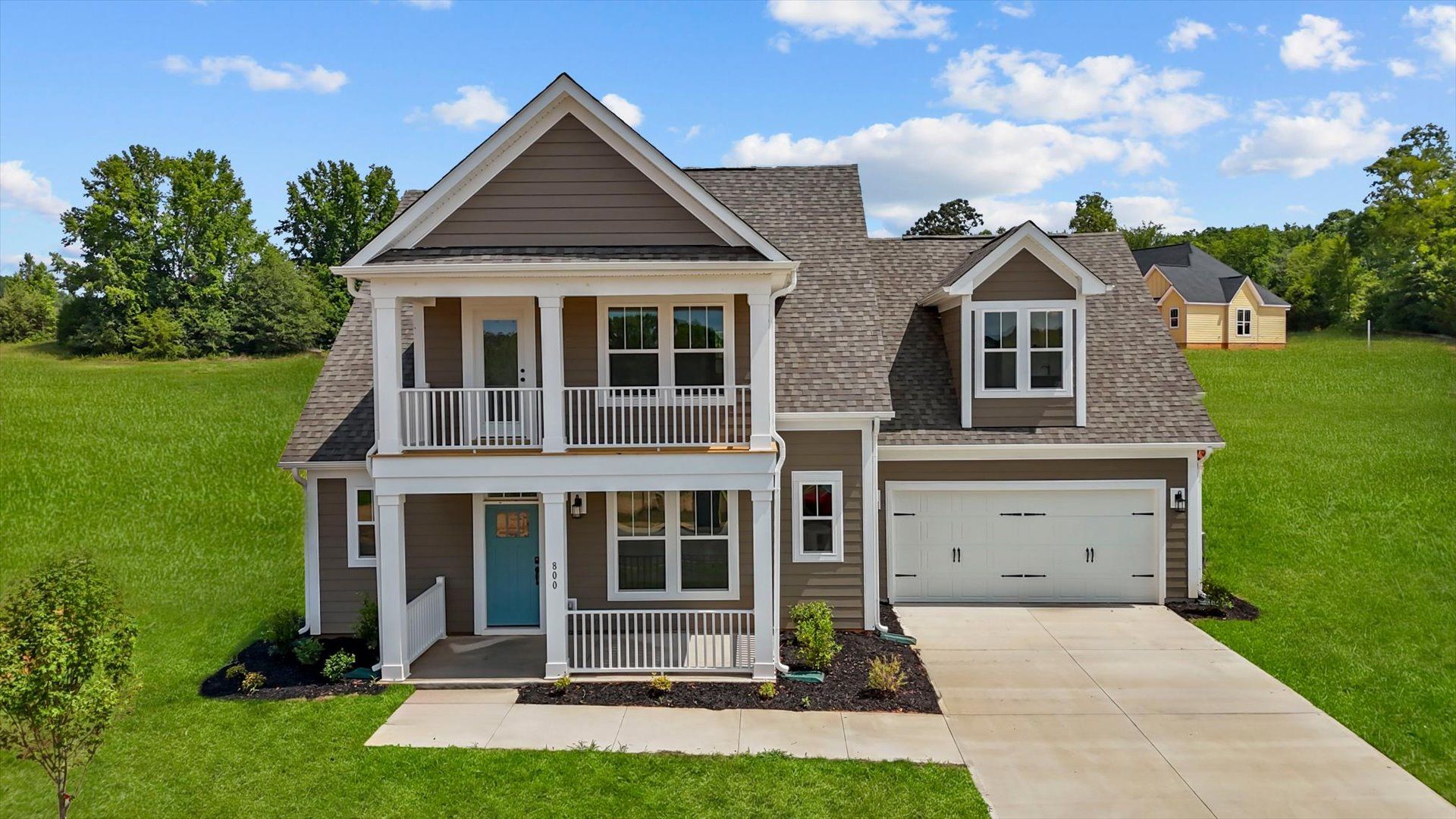 Exterior of two story home with second story front balcony at Pinebrook by DRB Homes