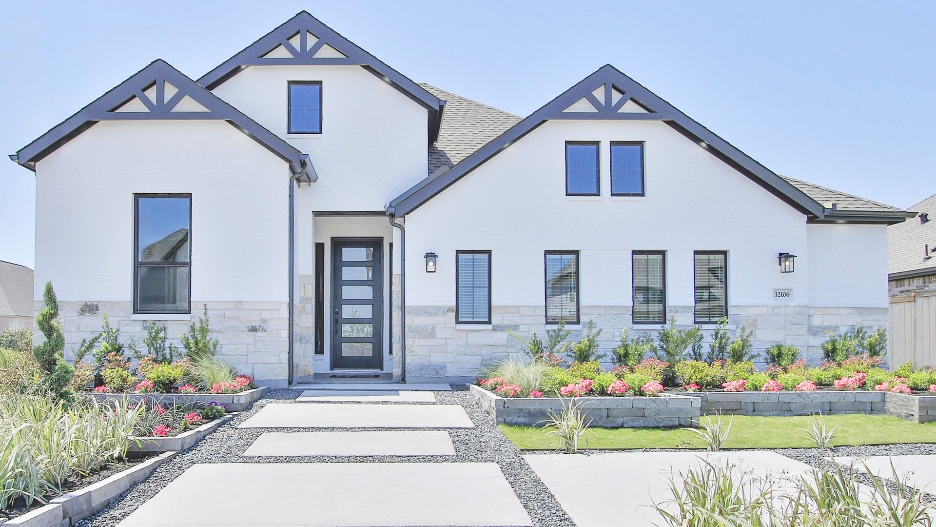 Modern White House in Oakwood Estates with Black Trim and Garden:Elegant white facade with black accents, lush landscaping, and stone elements in Oakwood Estates.