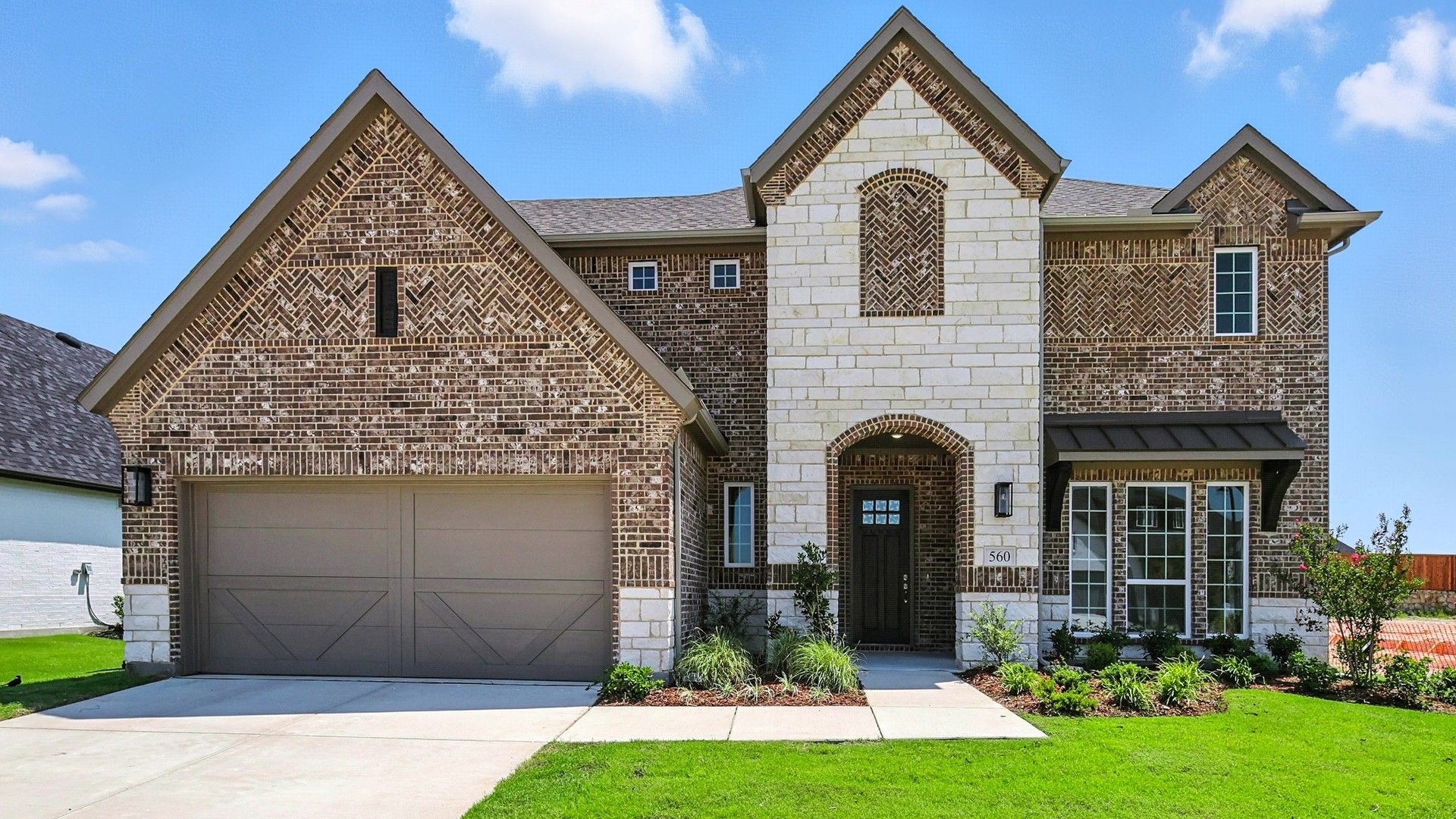Elevation F:Exquisite stone façade and expansive windows define this Ridge Crossing residence's modern elegance.