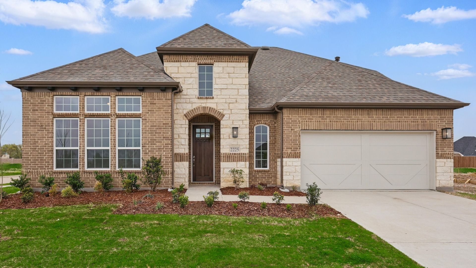 Elegant Brick Home with Stone Accents in Princeton at Ridge Crossing:Luxurious brick facade with intricate stone detailing and expansive windows in Princeton at Ridge Crossing.
