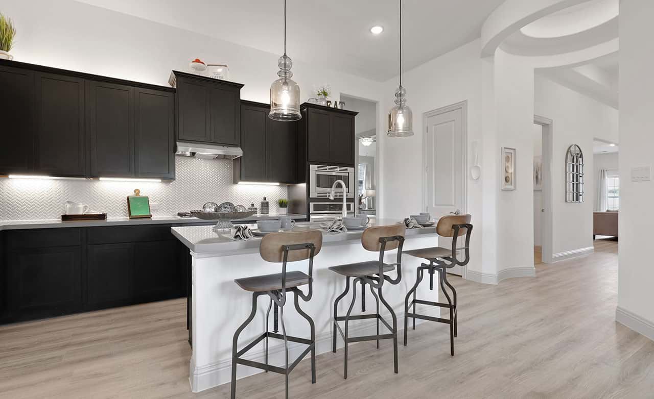 Elegant Kitchen Design at Thompson Farms with Dark Cabinets and Island:Luxuriate in Thompson Farms with exquisite dark cabinetry, striking herringbone backsplash, and stunning pendant lighting.