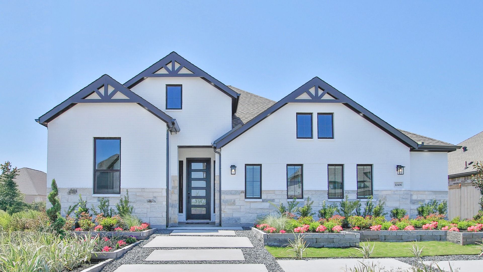 Modern White House in Oakwood Estates with Black Trim and Garden:Elegant white facade with black accents, lush landscaping, and stone elements in Oakwood Estates.