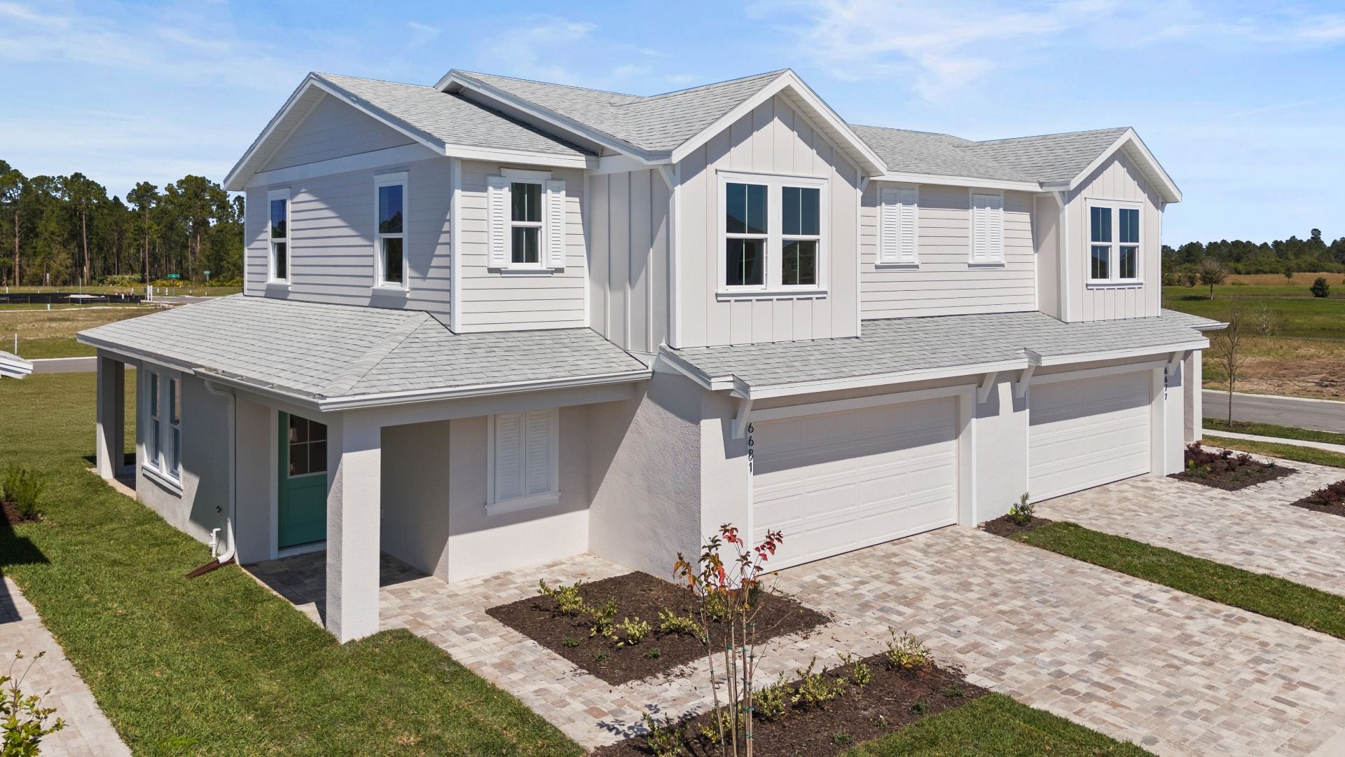 Cyrene at Harmony Outside:Cyrene at Harmony by DRB Homes features a paver driveway and walkway, enhanced by beautiful landscaping and serene lake views